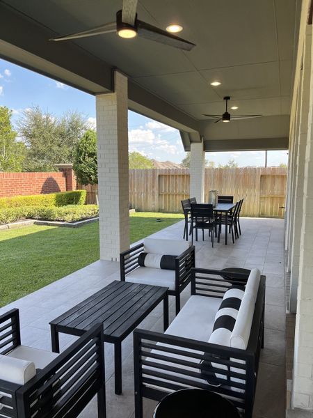 A stylish patio with sleek black furniture, ceiling fans, and a spacious lawn, perfect for outdoor relaxation. A stylish patio with sleek black furniture, ceiling fans, and a spacious lawn, perfect for outdoor relaxation.