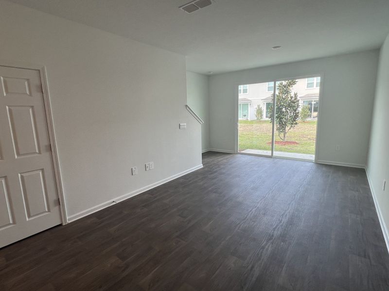 A spacious living area with dark wood floors, white walls, and a large sliding glass door to a serene garden view. A spacious living area with dark wood floors, white walls, and a large sliding glass door to a serene garden view.