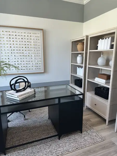 A modern office space with a sleek black glass desk, minimalist shelves, and artistic decor. A modern office space with a sleek black glass desk, minimalist shelves, and artistic decor.