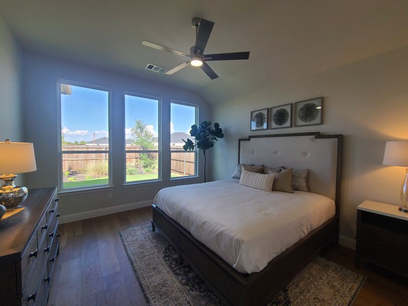 Cozy bedroom featuring a plush bed, elegant decor, and large windows with natural light and garden views.