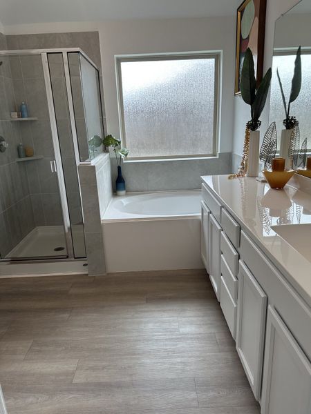 A modern bathroom featuring a glass shower, spacious tub, and sleek white vanity with decorative accents. A modern bathroom featuring a glass shower, spacious tub, and sleek white vanity with decorative accents.