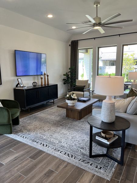 A modern living room featuring a sleek TV, elegant furniture, and abundant natural light.