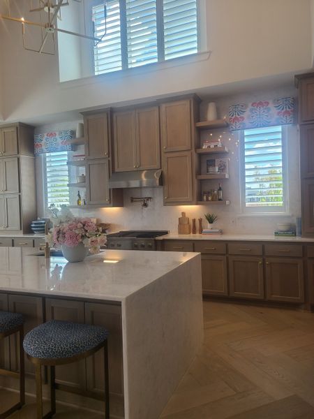 A modern kitchen featuring a marble island, elegant cabinetry, and stylish lighting with a floral accent.