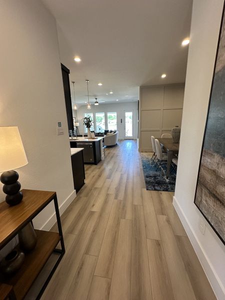 A modern open floor plan with sleek wood flooring, stylish lighting, and a cozy dining area.