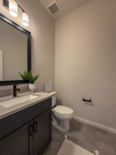 A modern bathroom featuring a sleek black vanity, stylish lighting, and contemporary tile flooring.
