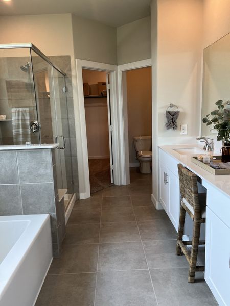 A contemporary bathroom with a glass shower, elegant vanity, and a cozy seating area.