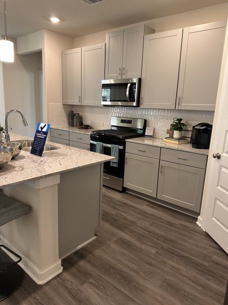 Modern kitchen with sleek gray cabinets, stainless steel appliances, and wood floors highlighted by white countertops. Modern kitchen with sleek gray cabinets, stainless steel appliances, and wood floors highlighted by white countertops.