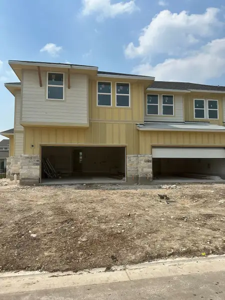 A modern yellow and cream-hued home with dual garages in Avery Centre by Landsea Homes (Round Rock, TX). A modern yellow and cream-hued home with dual garages in Avery Centre by Landsea Homes (Round Rock, TX).