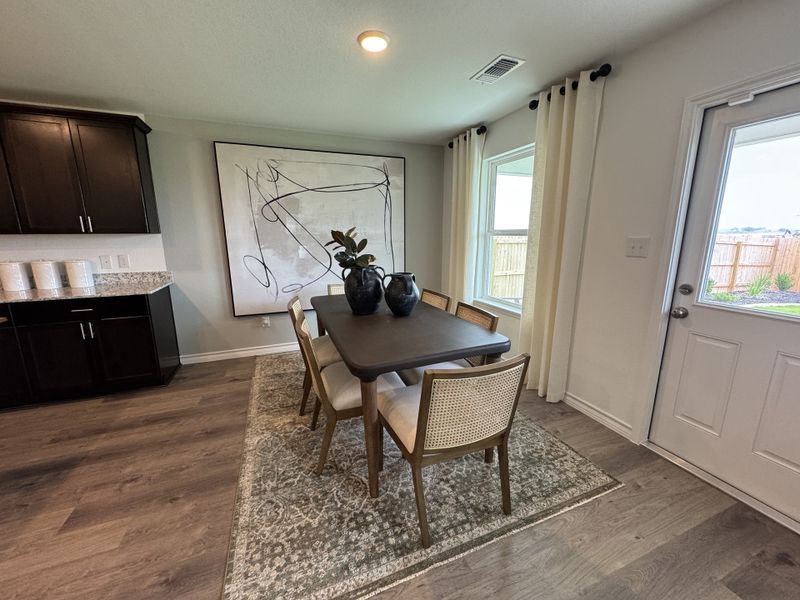 A cozy dining area with dark wood furniture, abstract art, and a large window letting in natural light.