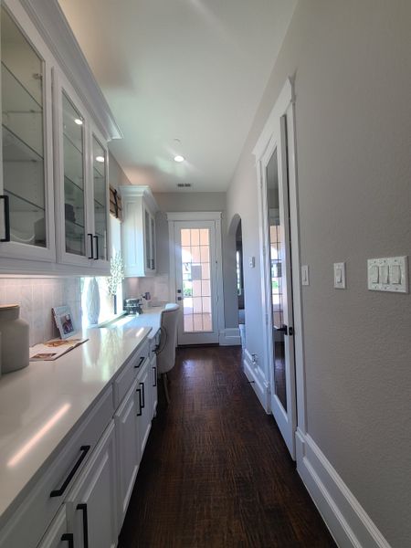A bright hallway with elegant cabinets, hardwood floors, and a cozy reading nook by the window. A bright hallway with elegant cabinets, hardwood floors, and a cozy reading nook by the window.