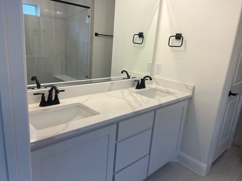 A modern bathroom with dual sinks, sleek black fixtures, and a spacious walk-in shower. A modern bathroom with dual sinks, sleek black fixtures, and a spacious walk-in shower.