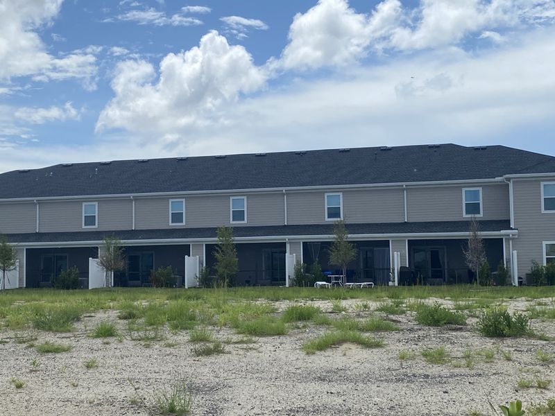 A modern townhome block with private patios and landscaped grounds in Mill Creek North Townhomes by Lennar (Jacksonville, FL).