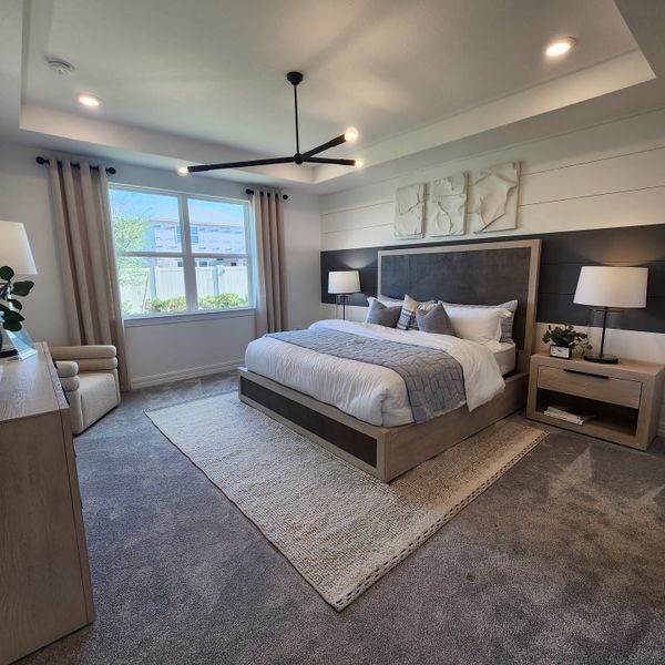 A modern bedroom with a plush bed, textured rug, elegant lighting, and a large window for natural light.