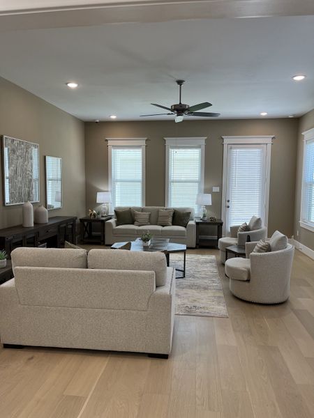 A cozy living room with neutral-toned sofas, sleek coffee table, soft lighting, and large windows for natural light.