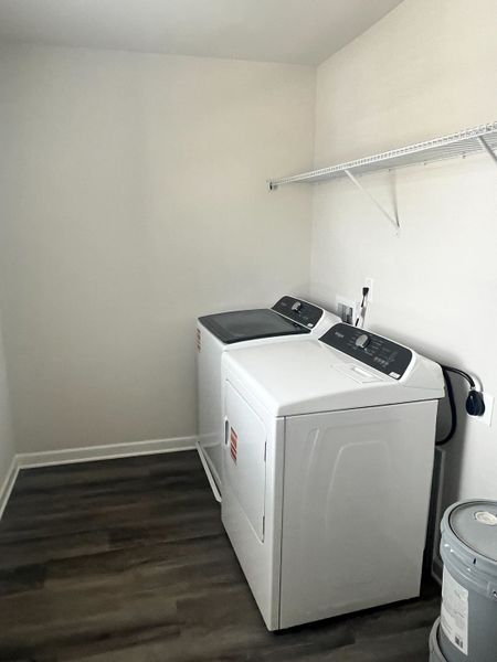 A modern laundry room with sleek appliances, laminate flooring, and an overhead storage shelf. A modern laundry room with sleek appliances, laminate flooring, and an overhead storage shelf.