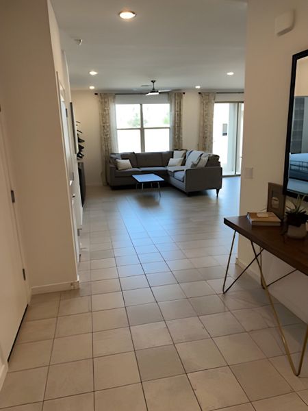 A bright living area with tiled flooring, a cozy sectional sofa, and large windows bringing in natural light. A bright living area with tiled flooring, a cozy sectional sofa, and large windows bringing in natural light.