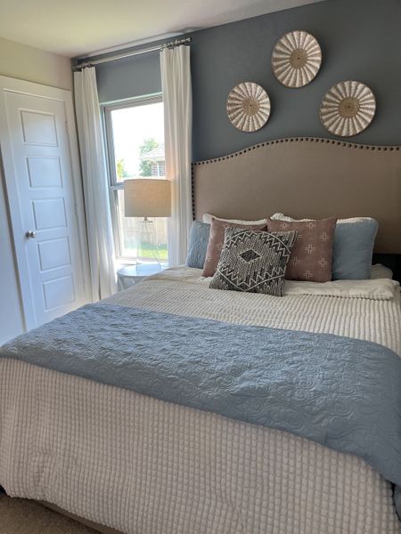 A cozy bedroom with a tufted headboard, elegant pillows, and calming blue and white decor.