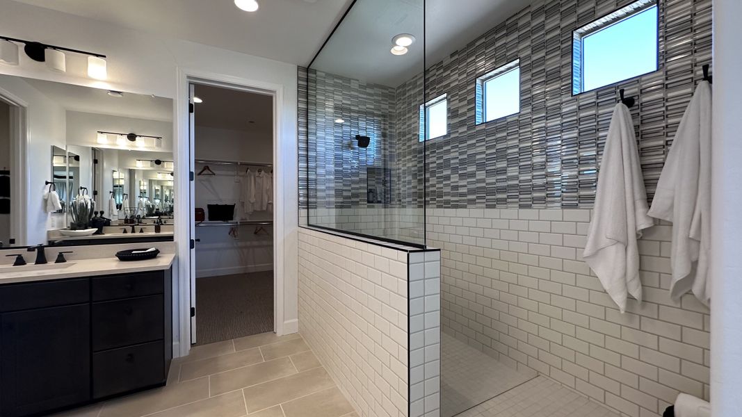 A luxurious bathroom with a glass-enclosed shower, modern vanity, and chic tile accents creating a stylish, serene space.
