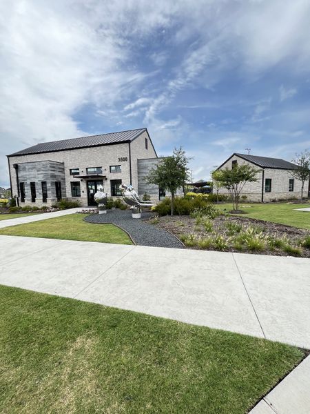 A modern white brick building with lush landscaping in Lakehaven by Trophy Signature Homes (Farmersville, TX).