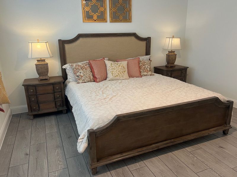 A cozy bedroom featuring a wooden bed frame, elegant side lamps, and intricate wall art above the headboard. A cozy bedroom featuring a wooden bed frame, elegant side lamps, and intricate wall art above the headboard.