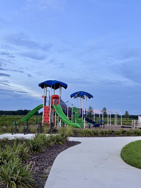 A vibrant playground with slides in Lakes at Bella Lago - Signature Series by Meritage Homes (Green Cove Springs, FL).