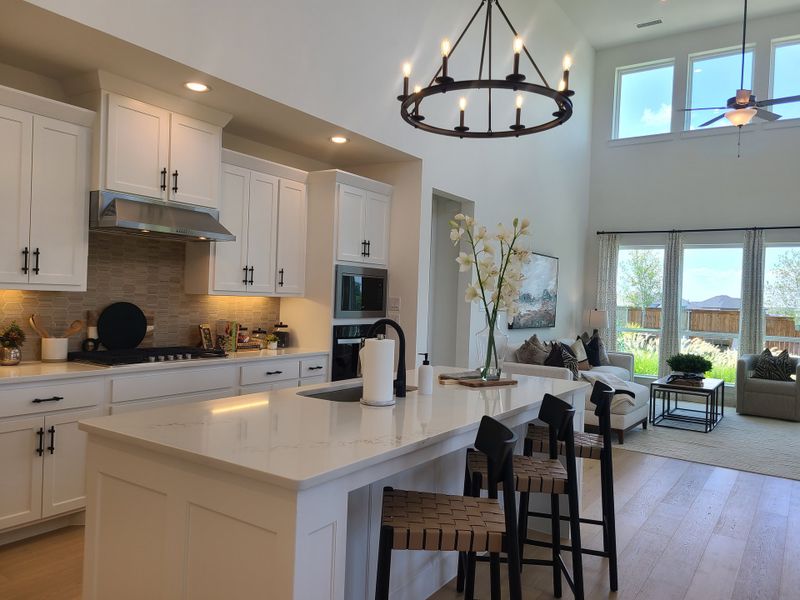 A bright, open-concept kitchen and living area with sleek white cabinetry, island seating, and large windows inviting natural light. A bright, open-concept kitchen and living area with sleek white cabinetry, island seating, and large windows inviting natural light.