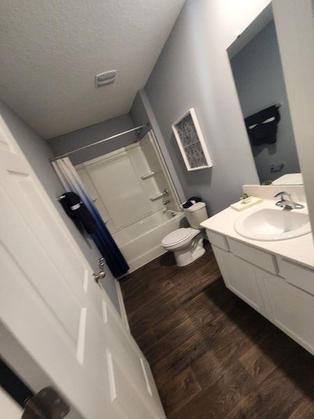 A sleek bathroom featuring wood flooring, a modern bathtub, elegant vanity, and soft gray walls. A sleek bathroom featuring wood flooring, a modern bathtub, elegant vanity, and soft gray walls.