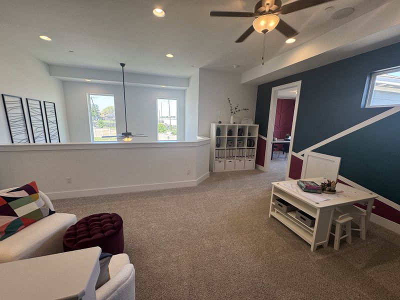 A cozy living space with modern decor, featuring a creative accent wall and ample light through large windows.