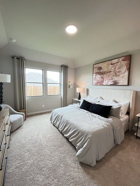 A cozy bedroom with a plush bed, abstract artwork, and large windows framed by elegant curtains.