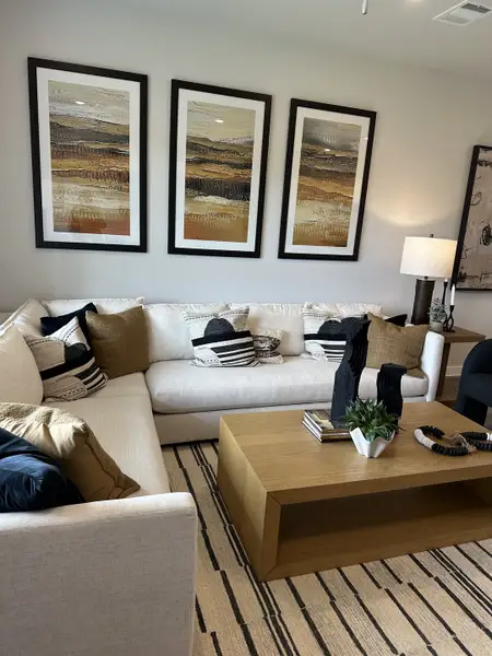 A cozy living room with a white sectional, stylish decor, and modern artwork, creating a warm and inviting atmosphere.