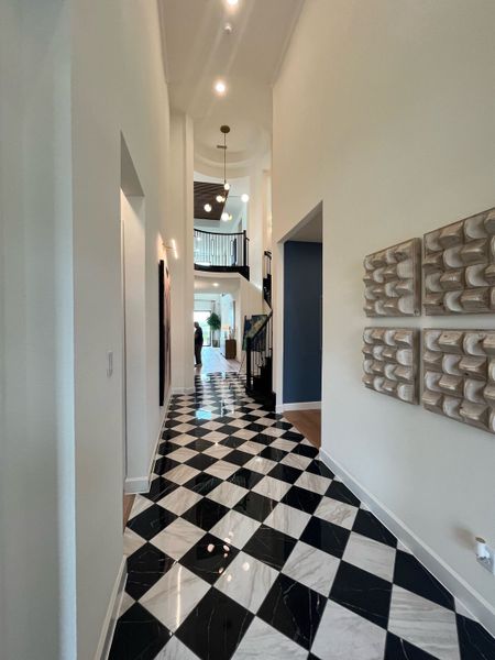 A chic hallway with black-and-white checkered flooring, modern wall art, and stylish lighting.