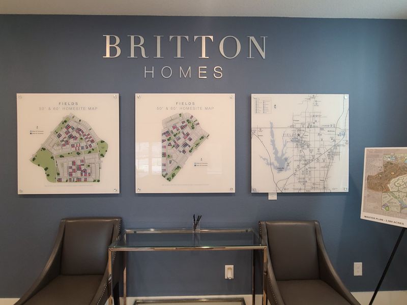 A chic office corner with a blue wall, elegant chairs, glass table, and homesite maps for Britton Homes.