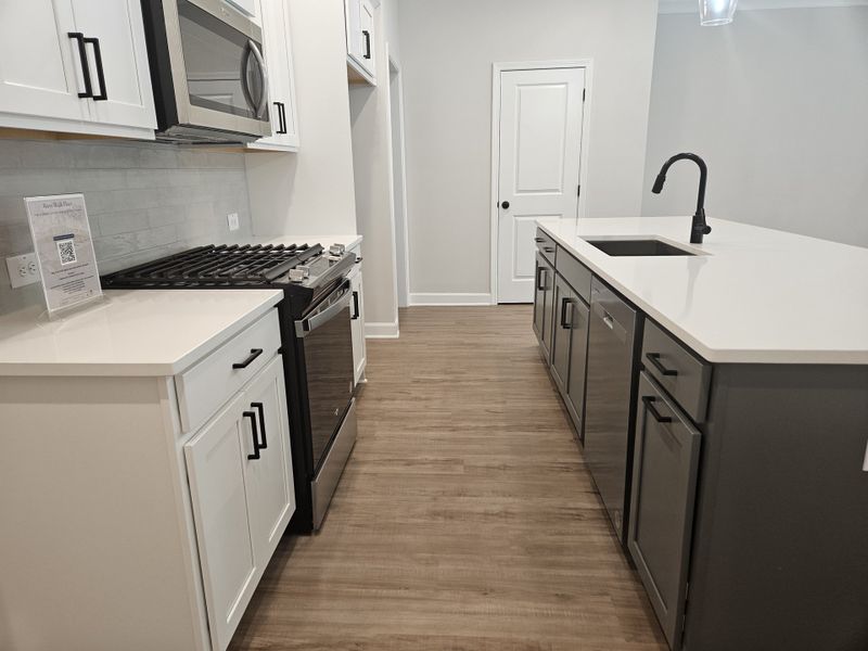 A modern kitchen with sleek cabinetry, stainless steel appliances, and quartz countertops featuring a center island.