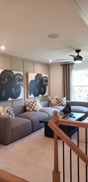 A cozy living area with a spacious gray sectional, abstract art, and soft lighting, offering a relaxing ambiance.