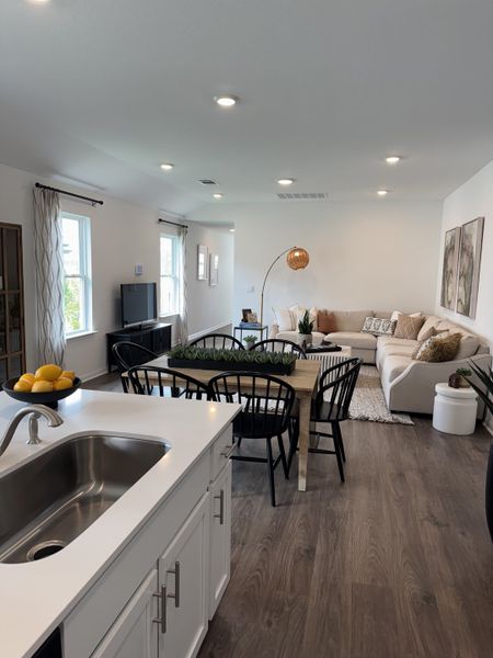 An open living area featuring a cozy seating arrangement, stylish dining set, and modern kitchen with sleek countertops.