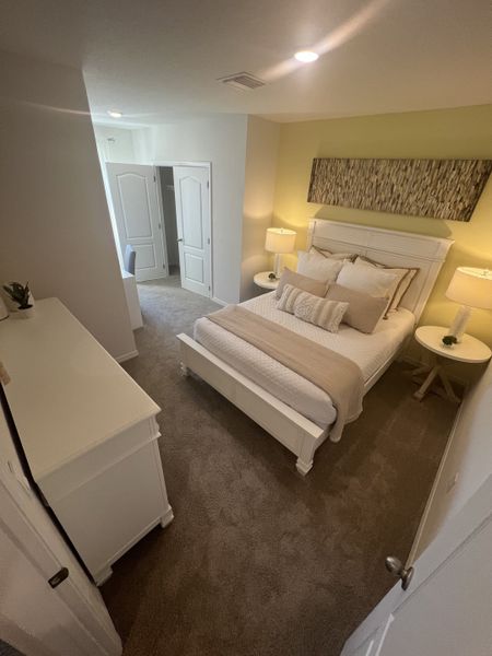 A cozy bedroom featuring a plush bed, soft lighting, and a stylish accent wall, creating a serene and inviting atmosphere.