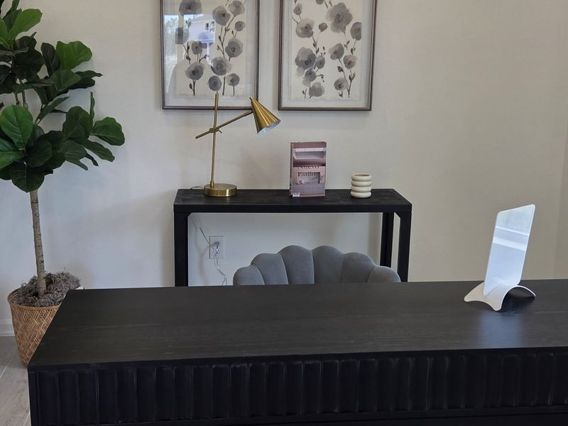 A chic office desk with modern decor, including a gold lamp, framed art, and a potted plant for a sophisticated touch.