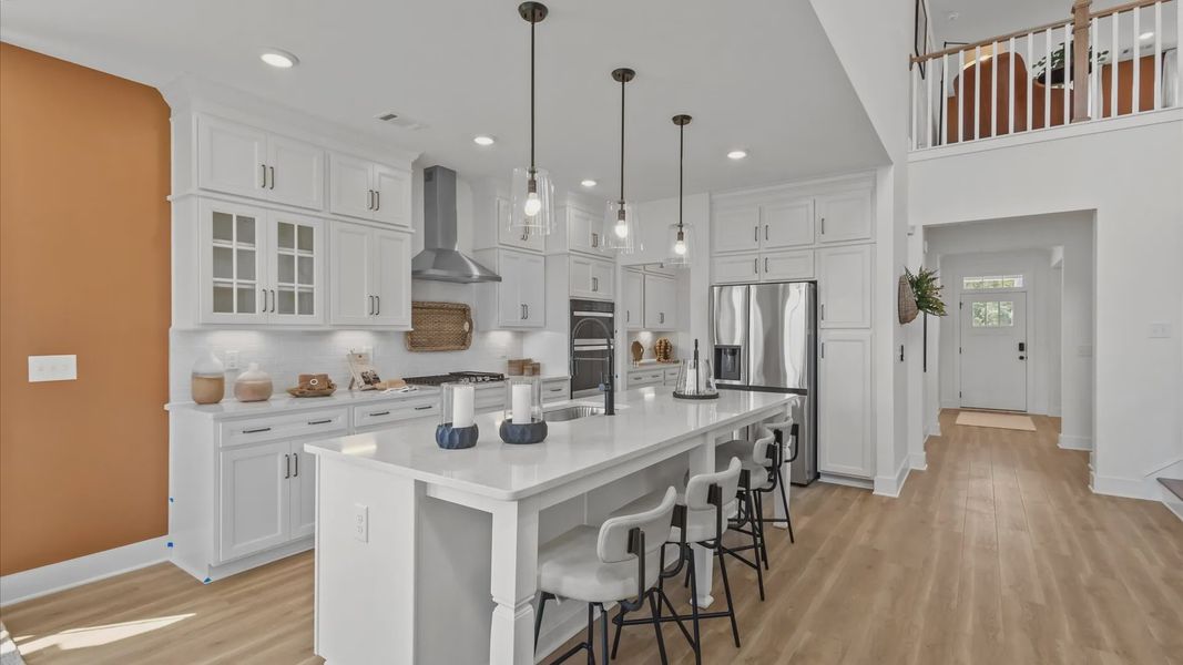 Kitchen in new two story home with built to ceiling white cabinets and large white island at Kayfield at Midway by DRB Homes