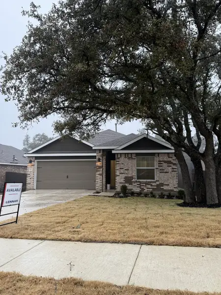 A charming brick home with a spacious garage and mature trees in Lively Ranch by Lennar (Georgetown, TX).