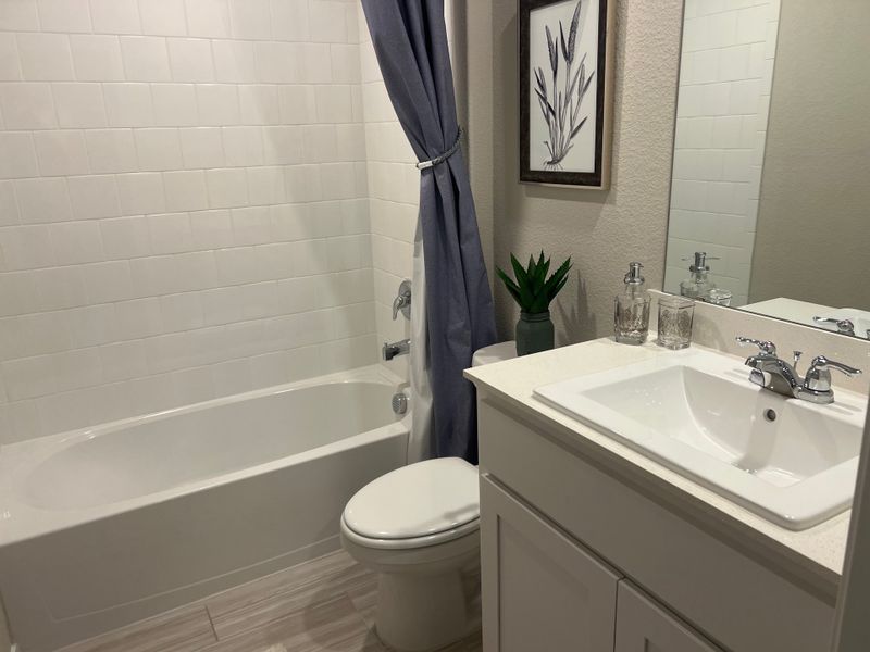 A contemporary bathroom with a sleek white vanity, elegant framed art, and a cozy bathtub with curtain. A contemporary bathroom with a sleek white vanity, elegant framed art, and a cozy bathtub with curtain.
