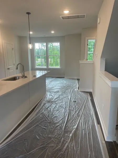 A modern kitchen with sleek countertops, pendant lighting, and large windows offering natural light.