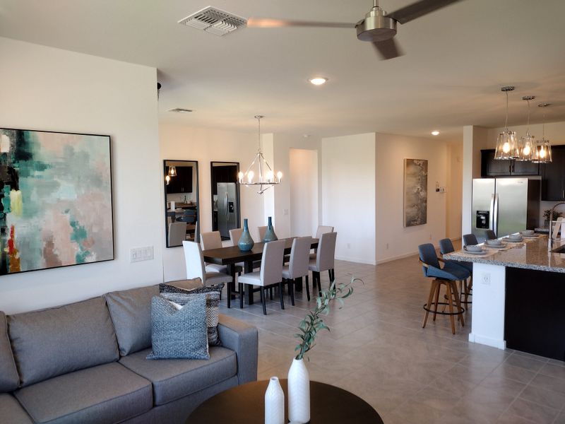 A modern, open-plan living area with a comfy gray sofa, chic dining set, and sleek kitchen island under stylish lighting. A modern, open-plan living area with a comfy gray sofa, chic dining set, and sleek kitchen island under stylish lighting.