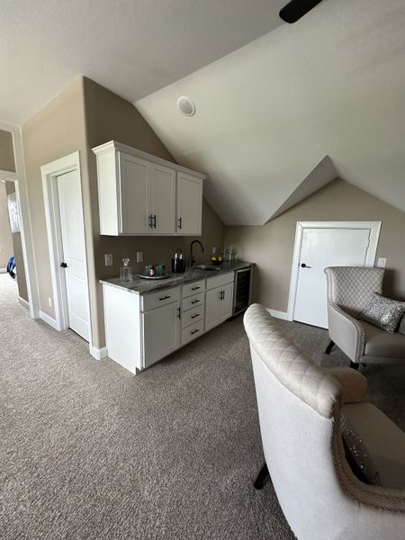 A cozy lounge area with plush chairs, a sleek wet bar, and modern cabinetry. A cozy lounge area with plush chairs, a sleek wet bar, and modern cabinetry.