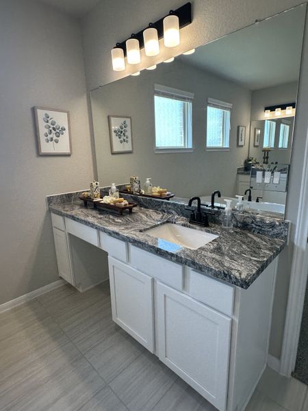 A modern bathroom features a granite countertop, sleek black fixtures, and ambient lighting for a stylish touch.