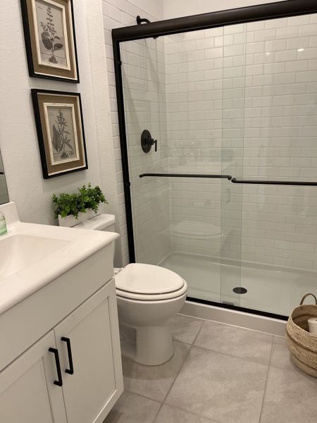 A modern bathroom featuring a sleek glass shower, white vanity, and elegant tile flooring.