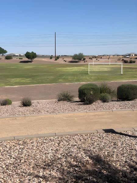 Expansive green field with goalposts in Magnolia at Desert Passage by KB Home (Maricopa, AZ), surrounded by desert landscaping.