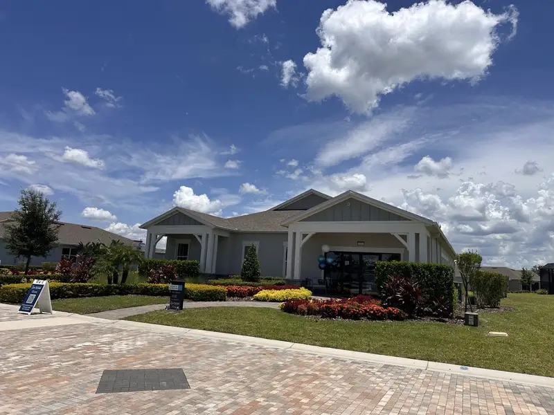 A charming home with manicured landscaping in Del Webb Oasis by Del Webb (Winter Garden, FL) under a vibrant blue sky.