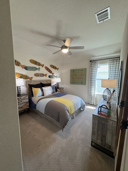 A cozy bedroom with colorful fish-themed decor, striped bedding, and ample natural light through the window.