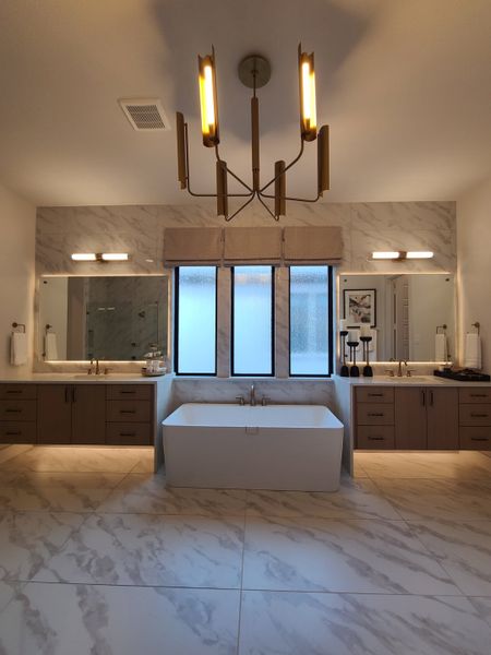 A luxurious bathroom with a sleek freestanding tub, dual vanities, and elegant lighting fixtures.