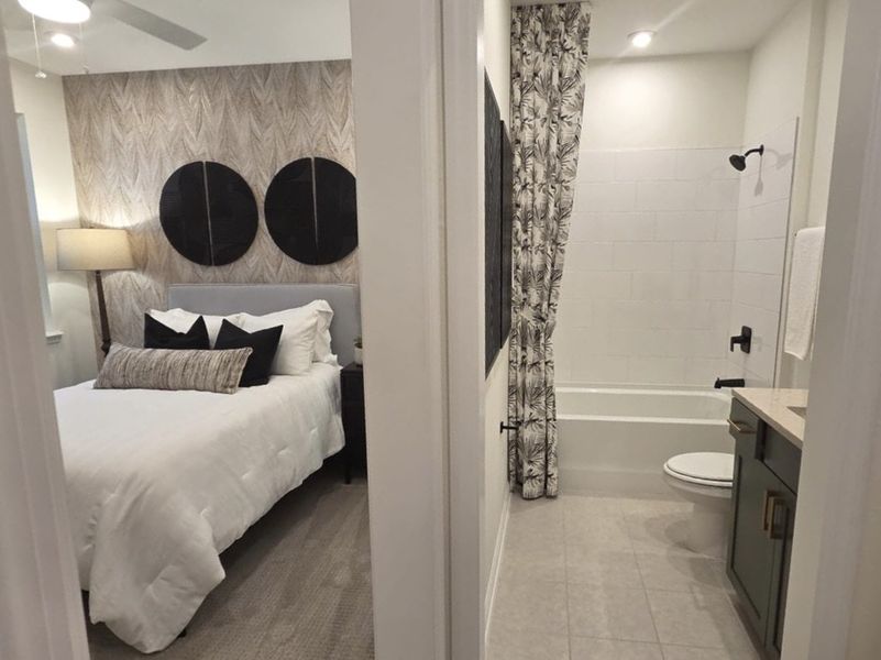 A cozy bedroom with patterned wallpaper and a chic bathroom featuring modern fixtures and elegant tile design.